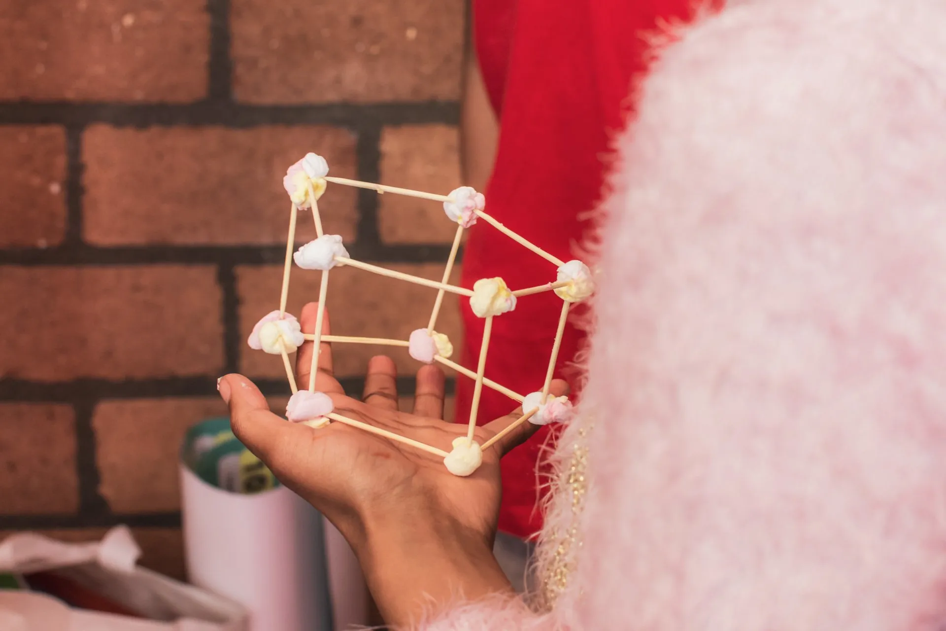 A child holding a 3D cube built from marshmallows and sticks during a maths activity