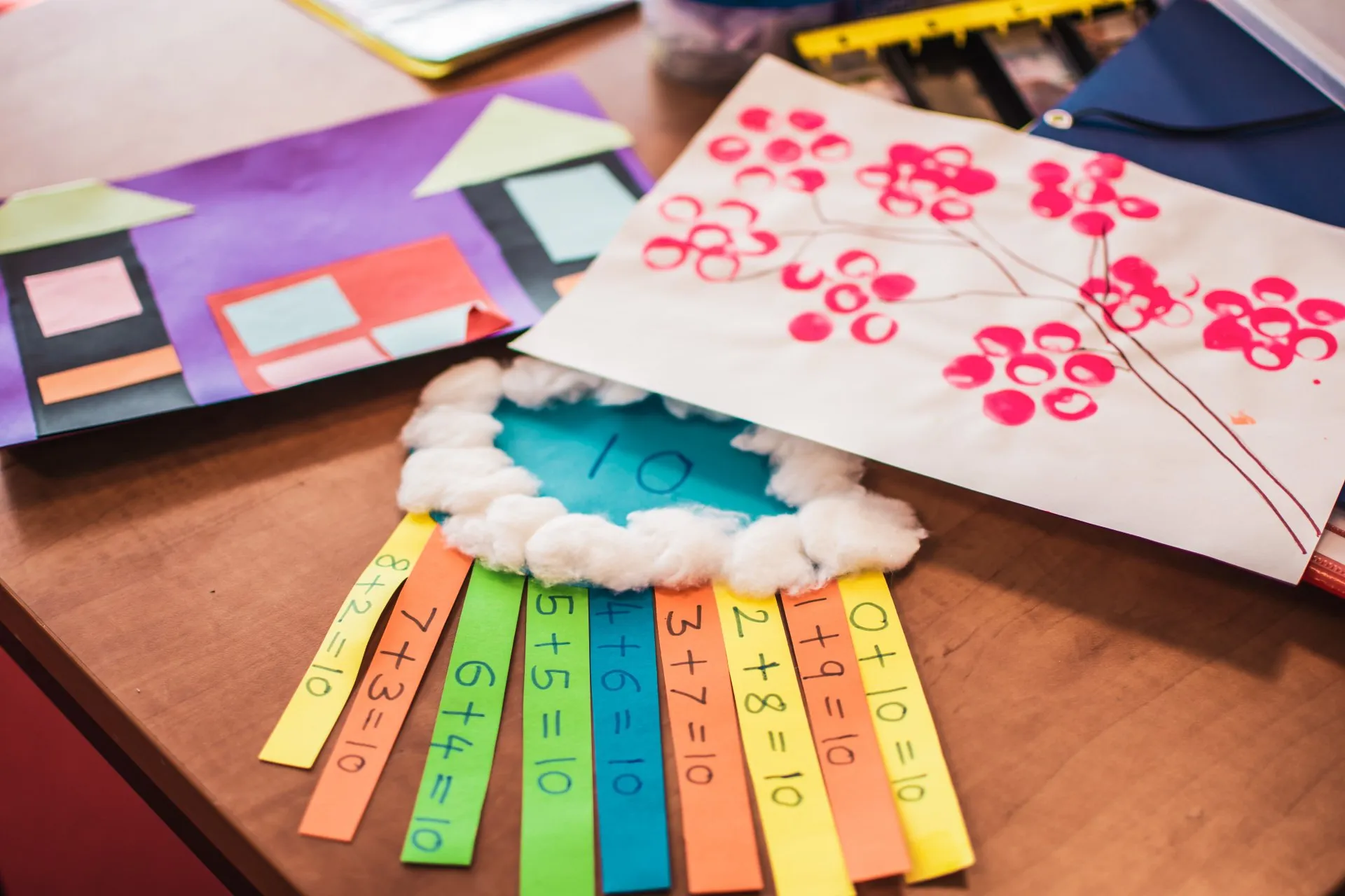Children's craftwork and a colourful 'make ten' addition rainbow activity on a table